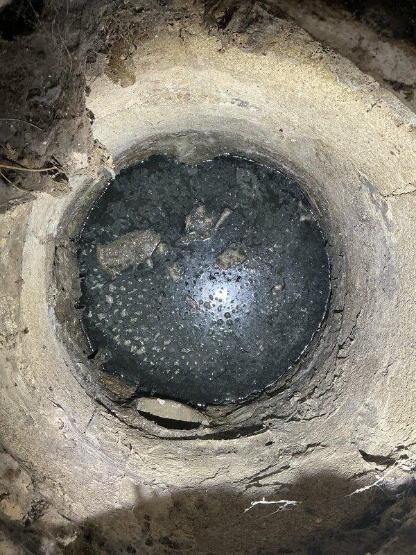 Responded to commercial property for clogged drain system in basement area. Upon arrival, located floor drain access point with standing water and active drainage issues. Inspected concrete drainage pit containing dark, stagnant water with visible bubbling, indicating blockage in the line. Performed drain cleaning procedures to clear obstruction and restore proper flow. Verified system functionality upon completion and documented conditions with photographic evidence of the drainage structure and surrounding work area.