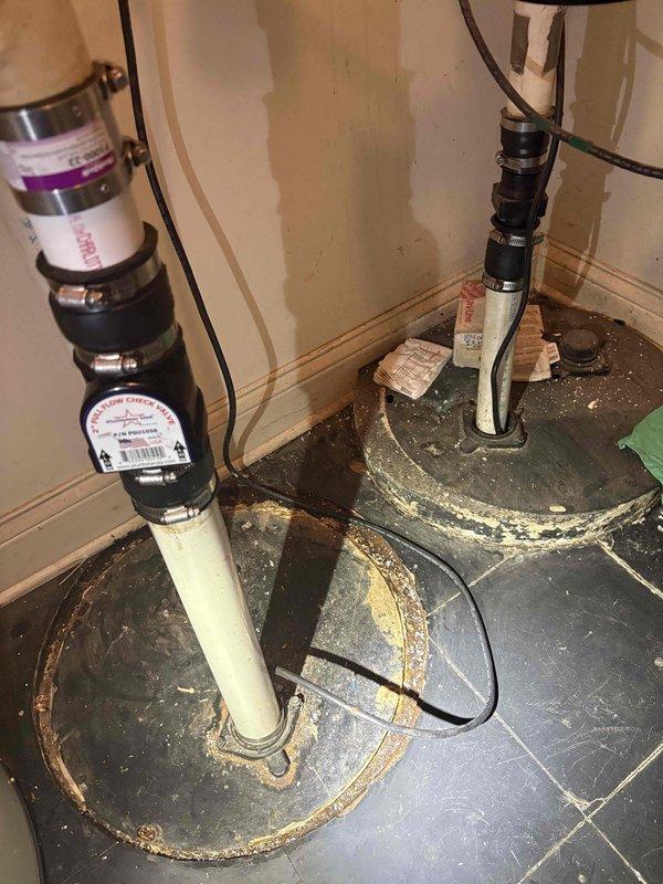 Responded to service call for noisy sump pump that was operational but unplugged due to excessive noise during operation. Upon inspection, found dual sump pump installation with visible signs of deterioration including rust staining, mineral deposits, and corrosion around floor-mounted bases and discharge piping connections. Documented existing conditions showing worn rubber couplings, corroded metal bases, and mineral buildup on both pump installations. Assessed pump performance and mechanical components to determine source of abnormal noise levels. Provided diagnostic evaluation and photographic documentation of equipment condition for repair estimate consideration.