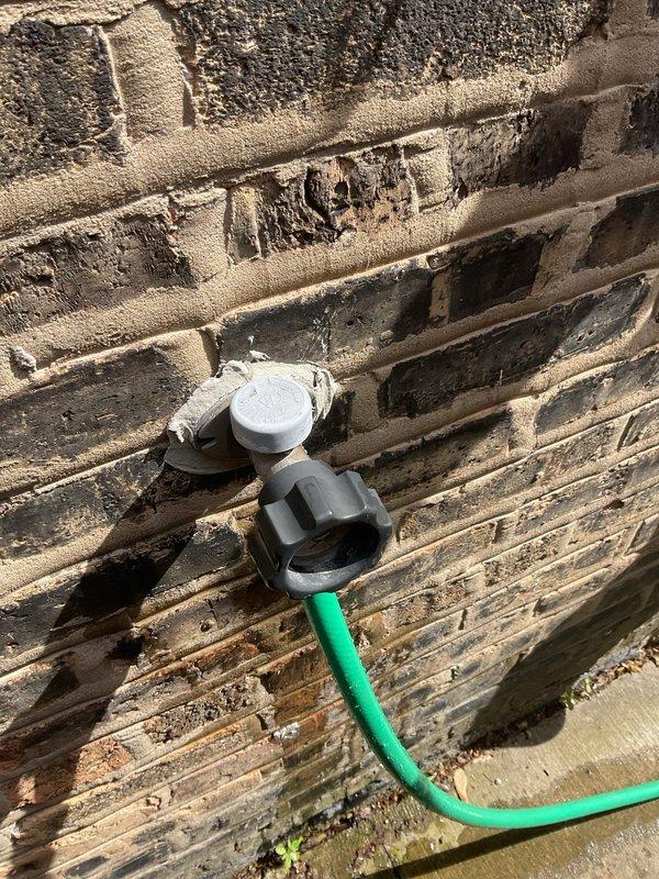 Responded to service call for assistance with two exterior water spigots requiring attention. Upon arrival, conducted thorough inspection of both outdoor hose bibs mounted on separate exterior walls. First spigot located on brick wall foundation with gray plastic fixture and white cap assembly. Second spigot positioned on significantly weathered horizontal wood siding showing extensive deterioration, peeling finish, and moisture damage. Evaluated both valve assemblies for proper operation, potential leaks, and freeze protection concerns. Documented existing conditions of mounting surfaces and fixture installations with photographic evidence. Assessed structural integrity of mounting locations, noting advanced wood deterioration on second spigot location requiring attention for proper fixture support. Provided professional assessment and prepared detailed estimate for necessary repairs or replacements to ensure reliable operation and prevent future water damage to building exteriors.
