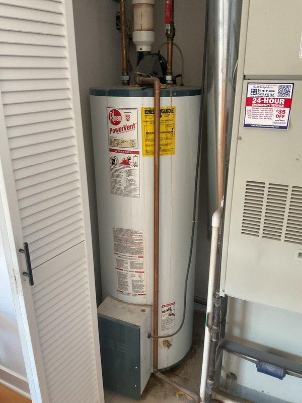 Responded to no hot water complaint and performed comprehensive inspection of Rheem PowerVent tanked water heater installation. Documented existing plumbing configuration including copper supply lines, ball valve shut-off assembly, PVC venting components, and integrated pump system. Photographed complete installation showing water heater positioned in utility closet alongside HVAC equipment, with visible pressure relief valve, multiple connection points, and proper venting arrangement to assess system condition and identify cause of hot water failure.
