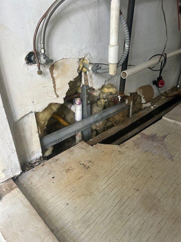 Completed plumbing estimate for piping replacement in basement utility area with deteriorated infrastructure and under-sink drainage system. Assessment included documentation of existing white PVC drain lines, copper supply lines, flexible stainless steel connectors, and P-trap assembly showing signs of age, water damage to surrounding wall surfaces, and compromised structural conditions requiring remediation.