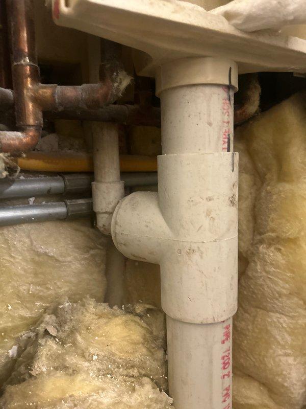 Completed plumbing estimate for piping replacement in basement utility area with deteriorated infrastructure and under-sink drainage system. Assessment included documentation of existing white PVC drain lines, copper supply lines, flexible stainless steel connectors, and P-trap assembly showing signs of age, water damage to surrounding wall surfaces, and compromised structural conditions requiring remediation.