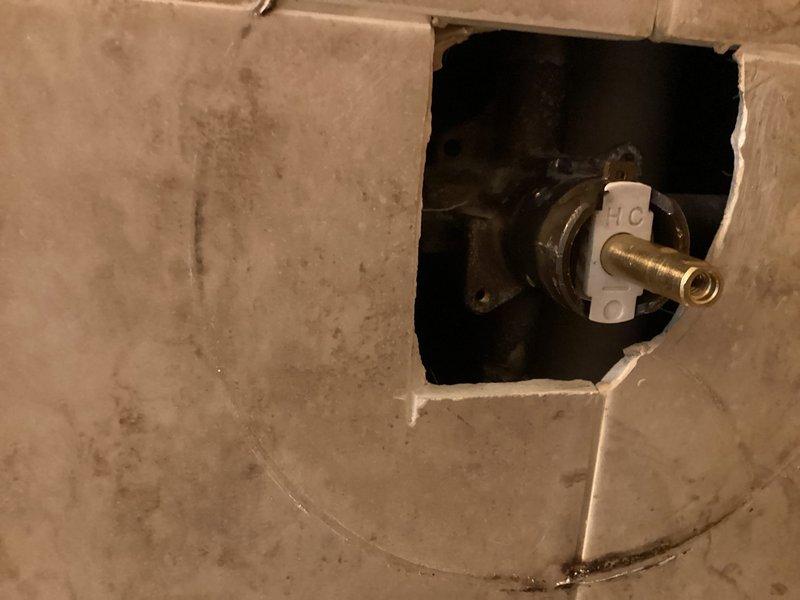 Responded to a Moen Posi-Temp shower valve failure where the handle hub assembly had seized on the stem, causing the cartridge stem to break during attempted removal. Accessed the valve from the rear wall opening and performed cartridge extraction to remove the broken stem and cartridge body that remained lodged in the valve housing. Installed new Moen Posi-Temp cartridge and completed trim kit installation with customer-supplied materials. Verified proper operation and confirmed no active leaks with water supply restored.