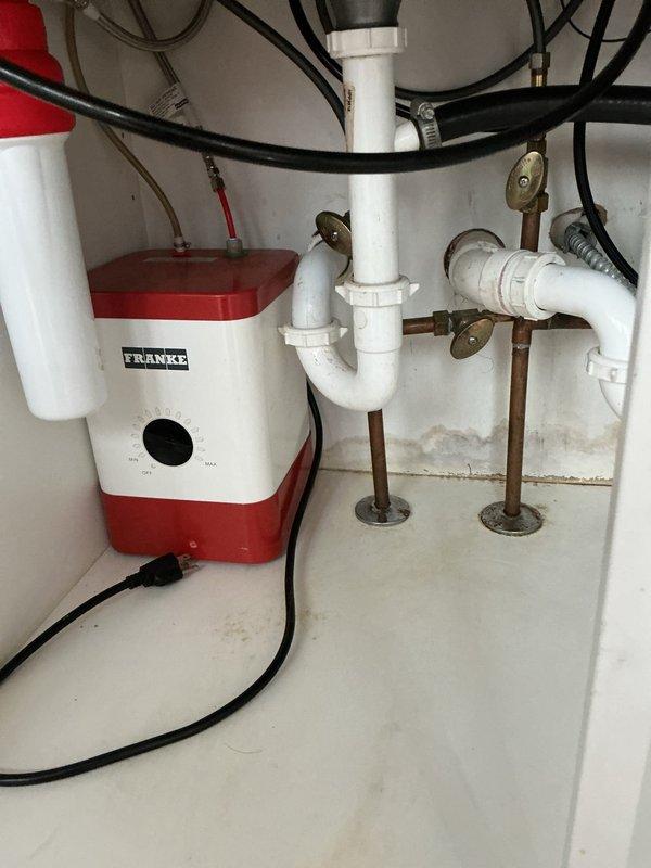 Responded to kitchen sink backup that had not been draining for approximately one week in a 25-year-old residential property. Upon inspection, identified the existing under-sink plumbing configuration featuring a Franke electric pump system integrated with white PVC drain lines and P-trap assembly. Assessed the complete drainage pathway including vertical and horizontal pipe sections, connection fittings, and pump unit functionality. Cleared the blockage and restored proper drainage operation. Verified all plumbing connections, hose clamps, and support brackets were secure and functioning correctly. System tested successfully with full water flow restored to kitchen sink drain.