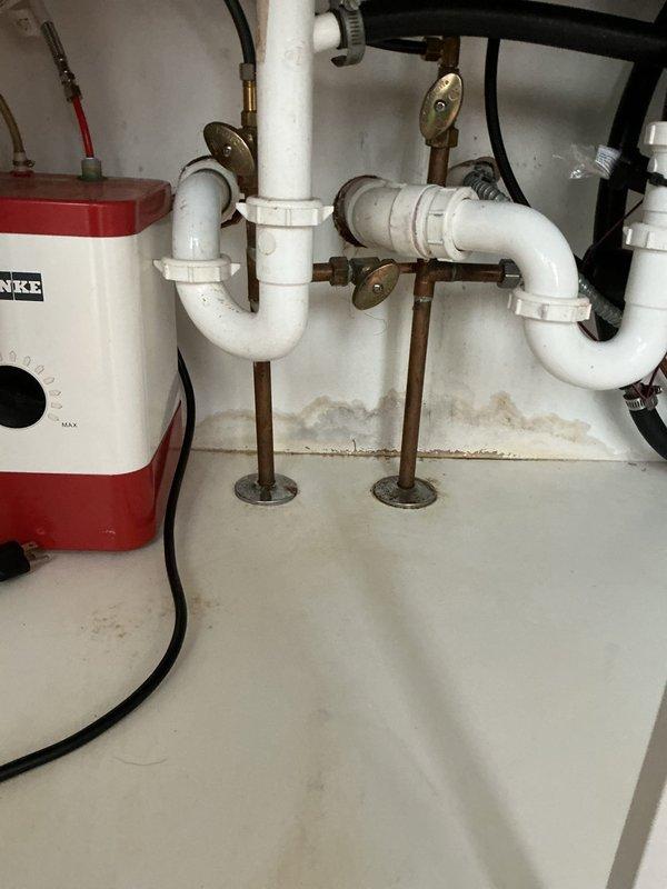 Responded to kitchen sink backup that had not been draining for approximately one week in a 25-year-old residential property. Upon inspection, identified the existing under-sink plumbing configuration featuring a Franke electric pump system integrated with white PVC drain lines and P-trap assembly. Assessed the complete drainage pathway including vertical and horizontal pipe sections, connection fittings, and pump unit functionality. Cleared the blockage and restored proper drainage operation. Verified all plumbing connections, hose clamps, and support brackets were secure and functioning correctly. System tested successfully with full water flow restored to kitchen sink drain.