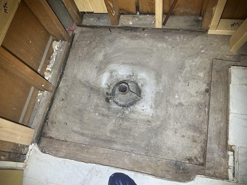 Responded to callback for new basement shower installation requiring underground drainage connection. Assessed existing 4" cast iron drain system showing significant corrosion and evaluated concrete floor conditions for proper drain tie-in. Documented heavily rusted standpipe assembly and existing floor drain opening with visible water staining indicating previous drainage concerns. Photographed newly installed shower pan with center drain assembly and surrounding wood framing to determine scope of underground piping work needed. Scheduled quality assurance specialist to provide detailed estimate for underground 4" cast iron drain line installation to connect new shower to existing drainage system.