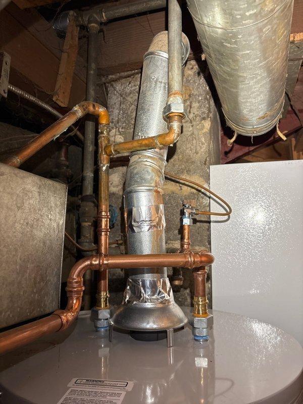 Upon arrival, discovered moisture on top of recently installed water heater. Further inspection revealed leak originating from an existing copper pipe fitting located just outside the scope of the original installation work. The problematic fitting showed signs of deterioration and was not part of the new water heater installation assembly. Documented the condition with photographs showing the copper piping configuration, connection points, and the source of the water intrusion. Scheduled follow-up visit to perform courtesy repair of the pre-existing fitting that was not identified during the initial installation.
