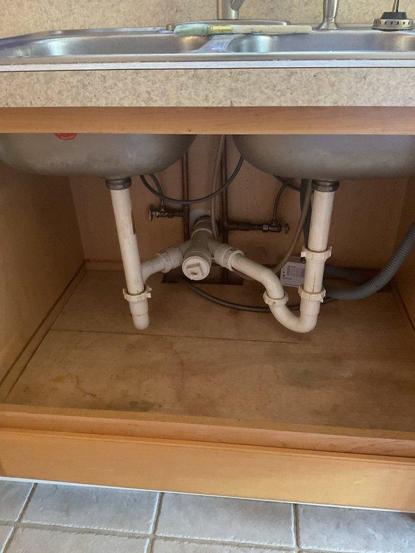 Responded to kitchen sink drainage issue affecting lower unit when upper unit fixtures were in use. Upon inspection, identified improper venting in the shared drain line causing backflow conditions between units. Accessed cabinet plumbing assembly and cleared obstruction from P-trap and connecting drain pipes. Removed accumulated debris and buildup from PVC drain system. Tested drainage flow from both upper and lower unit fixtures to verify proper operation and confirm elimination of backup condition. System functioning properly upon completion with no further backflow issues observed.