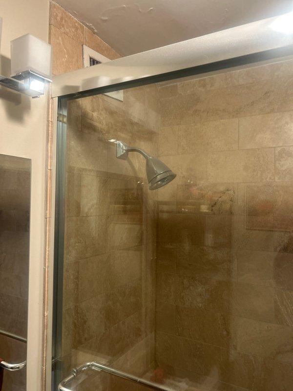 Responded to a shower leak affecting the ceiling of the unit below. Upon inspection, identified the shower mixer valve as the source of the water intrusion. Assessed the chrome shower control valve and fixtures mounted on the tile wall, documented the ceiling damage in the affected bathroom, and provided repair estimates to address the leaking mixer assembly and prevent further water damage to adjacent units.
