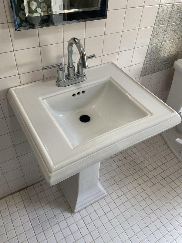 Responded to service call for multiple plumbing issues in 112-year-old residential property, including stopped toilet, clogged sink, and leaking toilet that had persisted for several months. Upon inspection, found vintage pedestal sink with chrome two-handle faucet and white porcelain toilet requiring attention. Cleared blockages from both toilet and sink drain lines using appropriate augering techniques for older plumbing systems. Addressed toilet leak by inspecting and servicing internal flush valve components and wax ring seal at floor connection. Evaluated existing brass/copper supply lines showing age-related tarnishing and oxidation, confirming proper function of wall-mounted shut-off valves. Due to advanced age of home's plumbing infrastructure, provided assessment of fixture conditions and drainage system performance. All fixtures restored to proper working order with adequate flow and drainage confirmed upon completion. Documented existing conditions of vintage plumbing compon