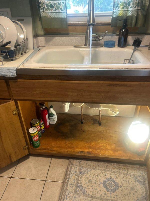 Responded to priority service call regarding leak underneath kitchen sink and low water pressure following previous service work. Inspected double-basin kitchen sink plumbing system and PVC drain connections beneath cabinet. Identified source of leak in drain assembly and verified water pressure at faucet. Tested both hot and cold water lines for proper flow and pressure. Tightened drain connections, inspected P-trap and tailpiece assemblies for proper seal. Verified all plumbing connections secure and leak-free. Confirmed water pressure restored to normal operating levels and no active leaks present upon completion of inspection and repairs.