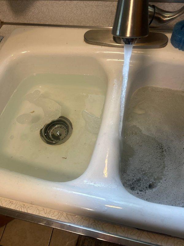 Responded to priority service call regarding leak underneath kitchen sink and low water pressure following previous service work. Inspected double-basin kitchen sink plumbing system and PVC drain connections beneath cabinet. Identified source of leak in drain assembly and verified water pressure at faucet. Tested both hot and cold water lines for proper flow and pressure. Tightened drain connections, inspected P-trap and tailpiece assemblies for proper seal. Verified all plumbing connections secure and leak-free. Confirmed water pressure restored to normal operating levels and no active leaks present upon completion of inspection and repairs.