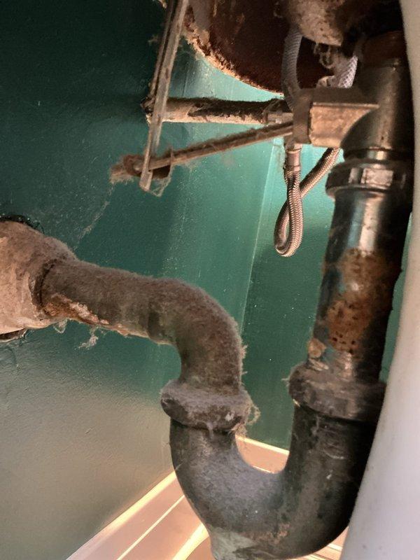 Responded to service call for bathroom sink with dual issues: active leak and slow drainage. Upon inspection, identified deteriorated drain assembly with corroded trap and compromised pop-up stopper mechanism causing drainage restriction. Addressed leaking condition at faucet connections and assessed aging plumbing infrastructure showing significant corrosion on supply lines and mounting hardware. Documented existing conditions of vintage three-piece faucet set with separate hot/cold handles and center spout, noting potential for future replacement due to age-related wear on fixtures and supporting plumbing components.