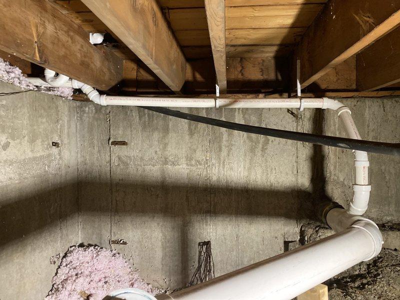 Inspected crawl space plumbing infrastructure and documented existing PVC drainage system configuration beneath structure. Evaluated condition of white PVC piping including horizontal runs and elbow connections installed along concrete foundation wall. Assessed crawl space environment noting moisture indicators on foundation surfaces and confirmed proper pipe routing through floor joist system. Repair work scheduled for completion at end of May or beginning of June per customer's request due to upcoming medical procedure.