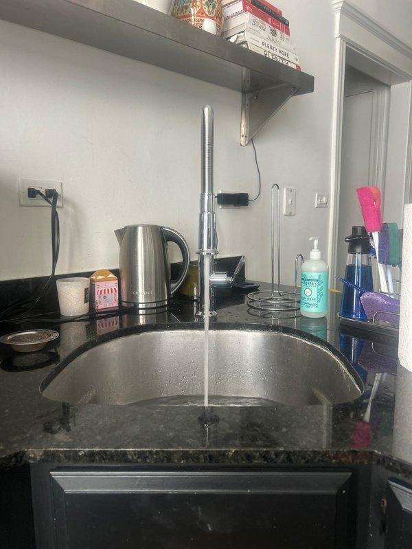 Successfully installed new kitchen faucet in undermount stainless steel sink with dark granite countertop. Addressed two existing issues with the cold water supply line: repaired dripping connection and resolved low pressure condition. Removed old faucet assembly, installed customer-provided gooseneck style chrome faucet, and ensured proper water flow and pressure to both hot and cold lines. Tested installation for leaks and verified optimal water pressure and temperature control functionality.