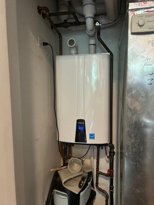 Responded to service call for Navien tankless water heater experiencing intermittent heating issues where unit would reach temperature but fail to maintain consistent hot water output. Performed diagnostic evaluation of 10-12 year old unit, inspecting digital control panel, examining all water and gas connections, and verifying proper operation of condensate pump system. Documented existing installation configuration including copper supply lines, PVC venting, electrical connections, and mounting setup for service records and future reference.