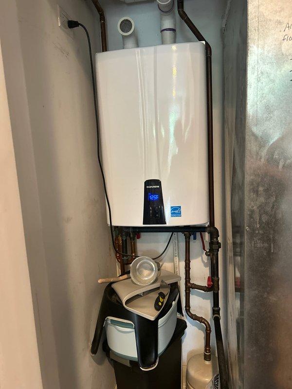 Responded to service call for Navien tankless water heater experiencing intermittent heating issues where unit would reach temperature but fail to maintain consistent hot water output. Performed diagnostic evaluation of 10-12 year old unit, inspecting digital control panel, examining all water and gas connections, and verifying proper operation of condensate pump system. Documented existing installation configuration including copper supply lines, PVC venting, electrical connections, and mounting setup for service records and future reference.