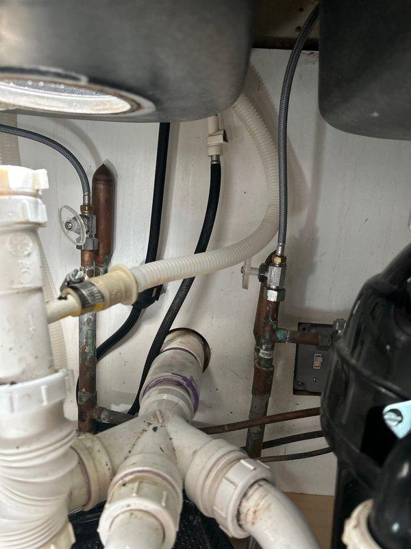 Conducted on-site assessment for installation of Aqua Sauna filtration system in residential property. Inspected existing under-sink plumbing infrastructure and utility cabinet space, documenting extensive corrosion on metal pipe fittings, rust deterioration on vertical supply lines, and verdigris buildup on copper connections. Evaluated current configuration including flexible supply hoses, shut-off valves, and electrical connections to determine compatibility requirements and necessary modifications for whole-home water treatment system integration.
