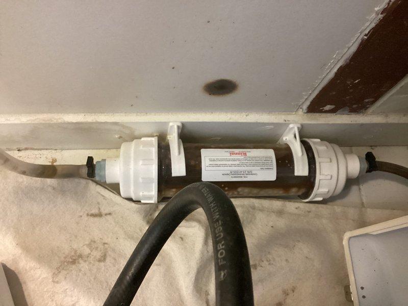 Completed VIP plumbing maintenance inspection involving water filtration system and concealed plumbing infrastructure. Accessed wall cavity to examine copper piping connections and insulation condition around plumbing runs. Inspected horizontal whole-house water filter assembly with clear canister housing, verified mounting bracket integrity, and assessed sediment accumulation within filter cartridge to ensure proper water treatment system operation.