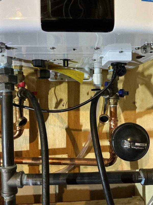 Performed complimentary VIP maintenance service on tanked water heater system. Conducted descaling flush procedure using chemical cleaning solution circulated through the tank and plumbing connections via pump and hose assembly. Inspected all inlet and outlet copper piping, compression fittings, and shut-off valves with red handles for proper operation and signs of corrosion or leaks. Verified integrity of flexible connector hoses and examined pressure relief components. Confirmed all mounting hardware secure and checked manufacturer specification labels for compliance. System flushed successfully, connections tested, and unit returned to normal operation.