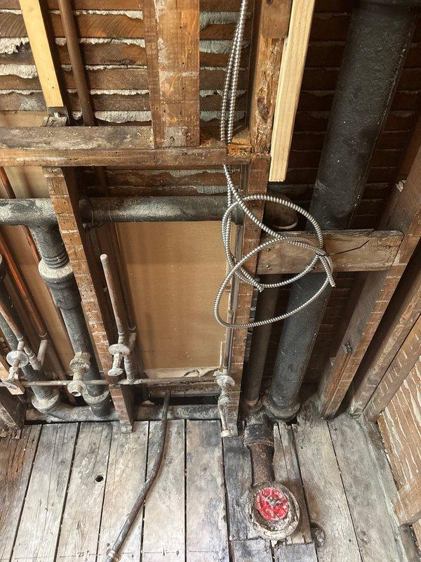 Completed shower/tub plumbing installation in basement area involving replacement of severely corroded drain flange and associated piping. Removed deteriorated metal components exhibiting extensive rust damage, installed new drain assembly with proper sealing, and configured supply lines to ensure code-compliant water delivery to new fixtures.