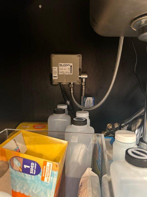 Responded to warranty call for intermittent electronic faucet sensor operation at commercial chocolate shop. Inspected Sloan electronic control unit and sensor assembly installed during previous service visit. Troubleshot LCE sensor functionality, checked battery power supply, verified electrical connections, and tested sensor response. Documented existing installation with photos showing electronic control box, flexible supply lines, shut-off valves, and under-sink plumbing connections for warranty records.