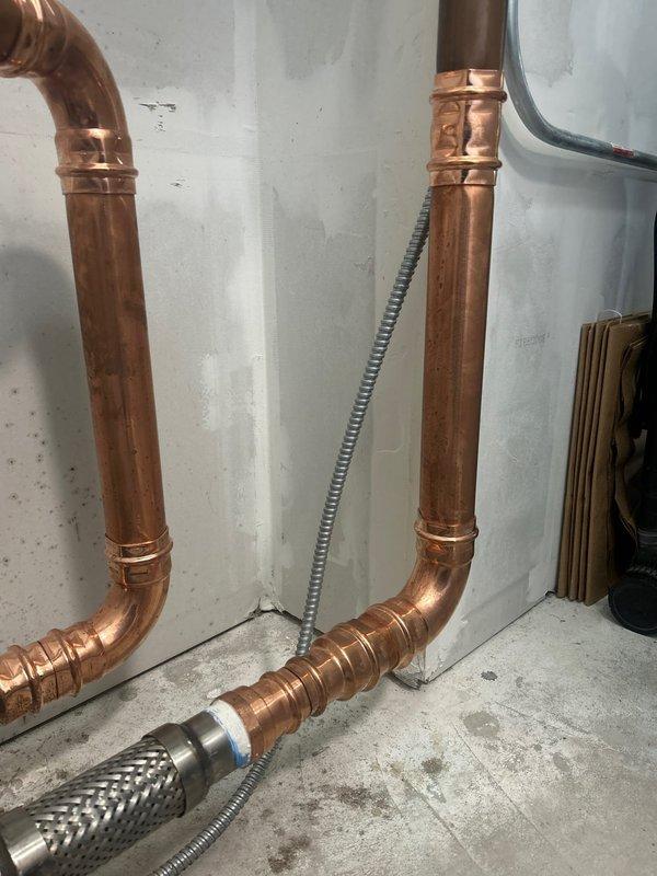 Performed diagnostic inspection of water pressure regulation system and hydronic plumbing assembly. Documented existing pressure gauge, brass fittings, copper piping with visible patina, check valve, and braided flex connections. Required replacement part has been identified and is currently available in shop inventory; follow-up appointment needed to complete installation and restore system to proper operating condition.