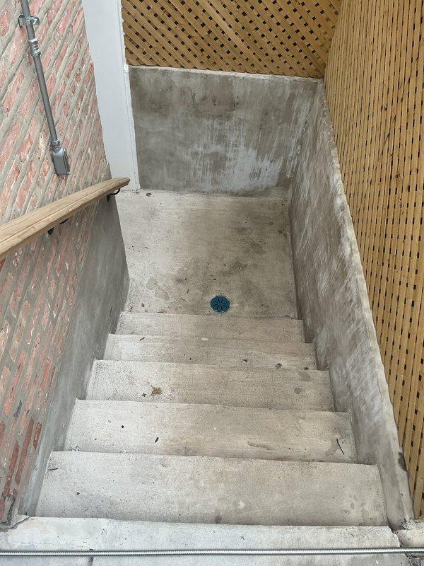 Conducted on-site assessment for installation of an external sewer backflow prevention valve at a residential property. Inspected exterior access point via concrete stairwell leading to lower level, documenting existing drainage infrastructure and potential installation location. Evaluated interior plumbing connections beneath kitchen sink to determine tie-in points for backflow preventer system and assessed compatibility with current PVC drain configuration.