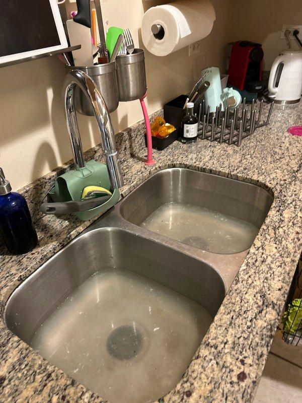 Responded to service call for standing water in double-basin kitchen sink and dishwasher. Upon arrival, confirmed both sink basins and dishwasher were filled with dirty water indicating a drainage obstruction in the common waste line. Deployed professional drain cleaning equipment including powered auger system to clear the blockage in the kitchen drain system. Successfully restored proper drainage function, allowing water to flow freely from both sink basins and dishwasher through the waste line.