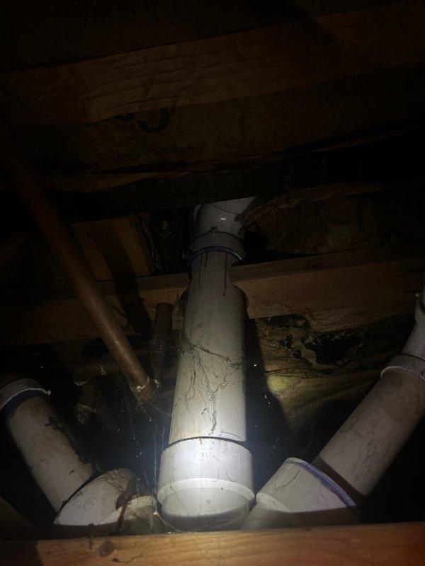 Conducted site visit to assess plumbing system in crawlspace area and provide estimate for additional work. Inspected existing PVC drain and vent stack configuration with multiple branch connections, noting visible wear, staining, and surface deterioration on piping. Documented copper supply line routing and overall plumbing infrastructure condition in confined access area beneath structure, photographing existing installation for estimate preparation.
