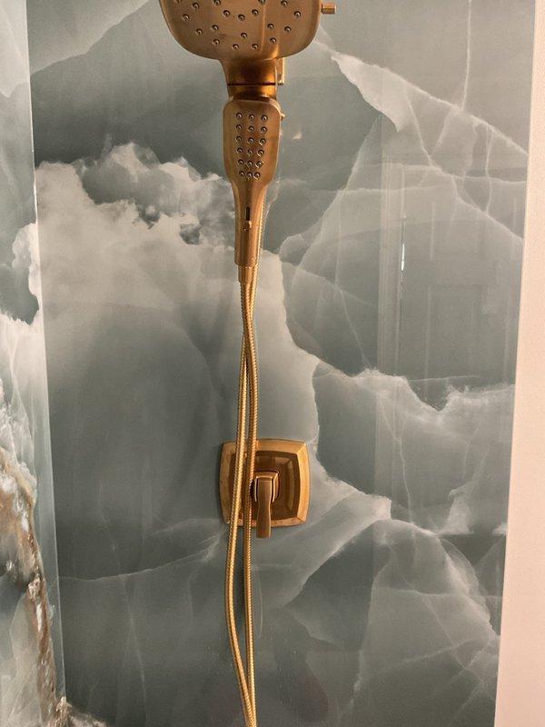 Conducted site assessment for shower fixture installation. Customer had showerhead assembly, handheld fixture, and handle trim parts on-site, but installation could not be completed due to missing shower arm and escutcheon in matching finish. Documented existing gold-tone handheld shower with flexible hose and wall bracket already installed. Explained to customer that additional components in correct finish are required before trim installation can proceed. Provided estimate for finish plumbing work to complete the fixture assembly.