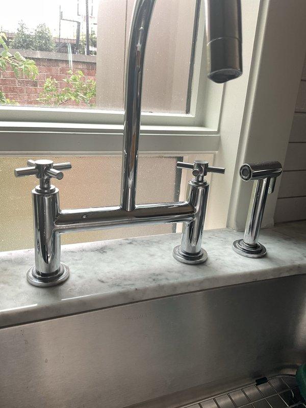 Completed diagnostic evaluation of two faucet issues in residential property. Inspected bridge-style Kohler kitchen faucet with dual cross-handle controls experiencing intermittent annual leaking. Assessed bathroom tub/shower diverter system where handheld spray function was inoperative, preventing proper tub filling. Documented existing fixtures and plumbing configuration with photographic evidence for repair recommendations.