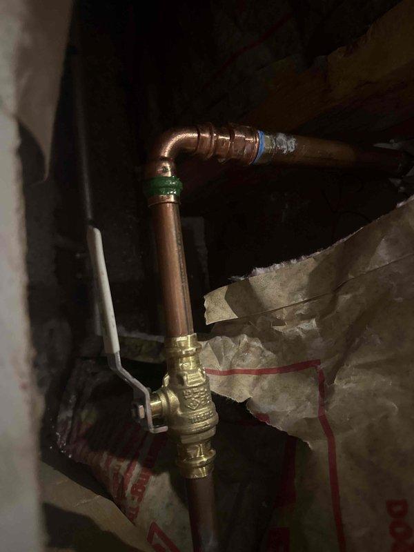 Responded to water leak emergency in residential property. Upon investigation, located source of leak in attic crawl space where copper supply line showed signs of failure at elbow joint connection. Inspected copper piping configuration with brass valve assembly and compression fittings surrounded by fiberglass insulation. Identified compromised joint as cause of water intrusion appearing on interior floor below. Repaired failed connection, tested system under pressure to verify proper seal, and confirmed no additional leaks present in accessible piping throughout the crawl space area.