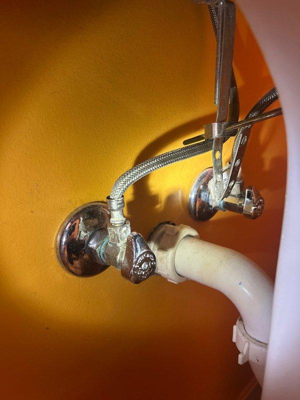 Completed installation of chrome single-handle faucet on Kohler bathroom sink with matching decorative cross-handle angle stop valves and braided stainless steel supply lines. All connections tested and verified leak-free with proper water flow and drainage function confirmed.