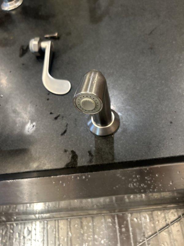 Responded to service call for kitchen sink faucet assembly. Upon inspection, found the spray nozzle required disassembly and servicing. Removed the chrome spray nozzle head from the mounting assembly and detached the white mounting bracket from the plumbing connection beneath the sink. Cleaned and inspected all components for wear, mineral buildup, and proper function. Addressed water flow issues and verified spray pattern functionality. Reassembled faucet components with proper seating of mounting hardware and tested for leaks. System restored to full operational status with proper water pressure and spray function confirmed.
