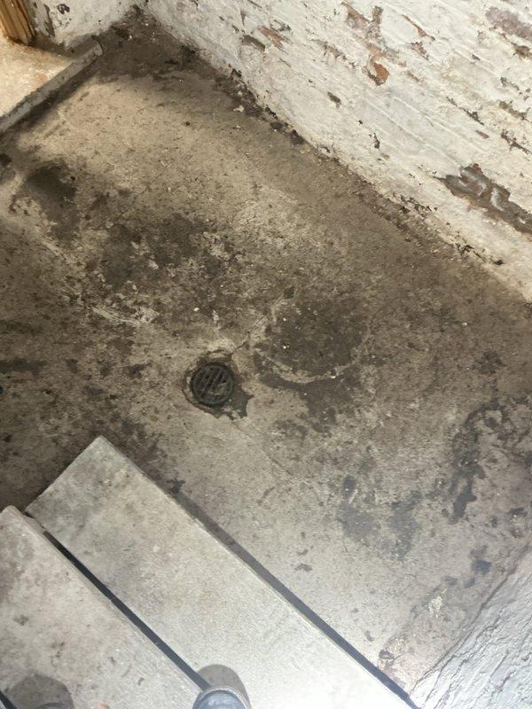 Responded to water backup through basement floor drain that occurs during rain events. Customer reported clear water with sewage odor backing up through drain in unfinished basement. Upon inspection, identified floor drain in deteriorated basement area with visible moisture damage to surrounding concrete and walls. Documented existing conditions showing compromised drain system and evidence of recurring water intrusion. Issue likely related to main sewer line obstruction or inadequate drainage capacity during heavy rainfall causing sewage backup through lowest point fixture.