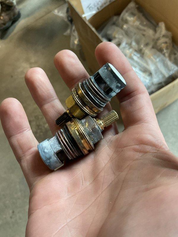 Replaced defective valve cartridges in kitchen bridge-style faucet assembly. Removed and installed new valve cores to restore proper water flow and temperature control to both hot and cold water handles.