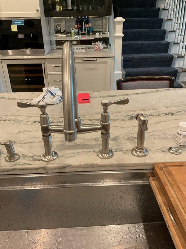Replaced defective valve cartridges in kitchen bridge-style faucet assembly. Removed and installed new valve cores to restore proper water flow and temperature control to both hot and cold water handles.