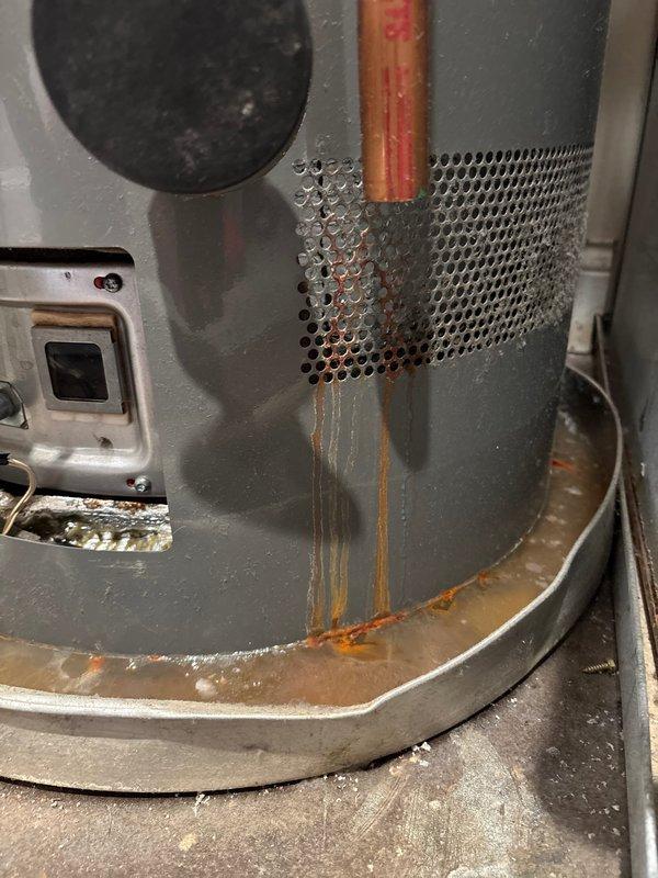 Responded to no hot water complaint with LCD error code 13 displayed on tanked water heater. Upon inspection, discovered significant water leakage from tank body with rust-colored water accumulation in drip pan and visible corrosion streaking down exterior of unit. Identified failed tank integrity as root cause of error code and loss of hot water. Documented extensive water damage and corrosion around copper pipe penetration point and base of unit. Advised that water heater has reached end of service life and requires complete replacement due to tank failure. Unit deemed unsafe for continued operation.