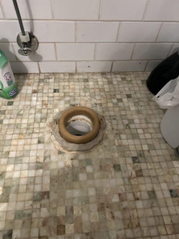 Responded to a toilet base leak in a basement unit bathroom. Upon inspection, found active water seepage at the toilet base with visible water staining and discoloration on the surrounding mosaic tile floor. Documented measurements and assessed the condition of the wax ring seal and flange connection. The leak pattern indicated a compromised seal between the toilet base and the drain flange, requiring toilet removal and reinstallation with new wax ring and hardware to restore proper watertight seal and prevent further water damage to the flooring.