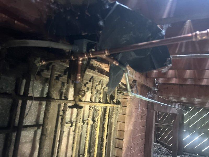 Responded to service call for leaking outdoor spigot. Inspected hose bib mounted on exterior brick wall and traced supply lines through attic space to identify source of leak. Evaluated copper piping connections and spigot valve assembly, documented existing conditions, and provided assessment of necessary repairs to resolve water leakage issue.