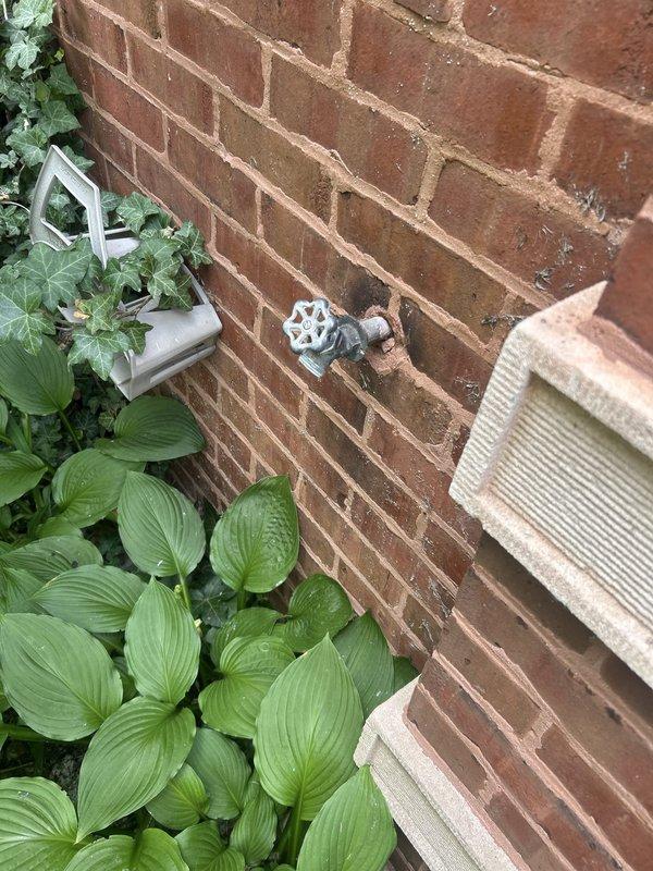 Responded to service call for leaking outdoor spigot. Inspected hose bib mounted on exterior brick wall and traced supply lines through attic space to identify source of leak. Evaluated copper piping connections and spigot valve assembly, documented existing conditions, and provided assessment of necessary repairs to resolve water leakage issue.