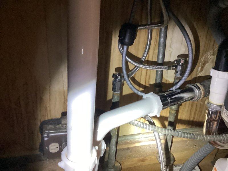 Responded to kitchen faucet leak complaint and performed comprehensive inspection of fixture and under-sink plumbing assembly. Upon examination, identified source of leak and assessed condition of chrome single-handle faucet, supply lines, and drain configuration. Documented existing plumbing setup including braided stainless steel supply hoses, P-trap assembly, and mounting hardware beneath double-basin stainless steel sink. Provided estimate for necessary repairs to resolve leaking condition.