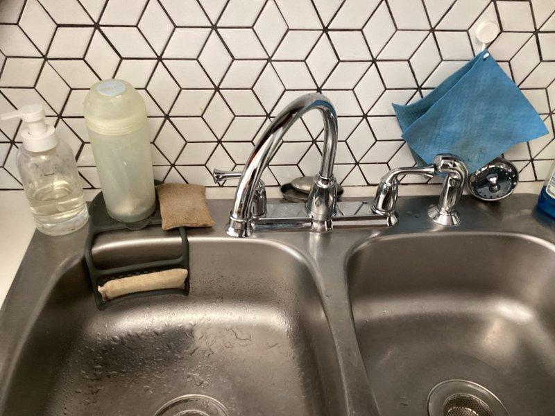 Responded to kitchen faucet leak complaint and performed comprehensive inspection of fixture and under-sink plumbing assembly. Upon examination, identified source of leak and assessed condition of chrome single-handle faucet, supply lines, and drain configuration. Documented existing plumbing setup including braided stainless steel supply hoses, P-trap assembly, and mounting hardware beneath double-basin stainless steel sink. Provided estimate for necessary repairs to resolve leaking condition.