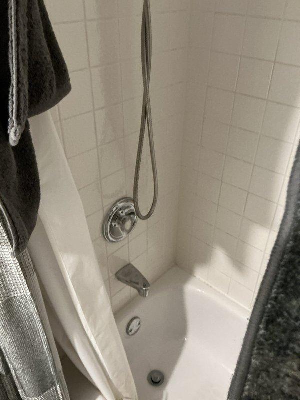 Responded to priority leak inspection request for water spot observed in area known as "the Zinger" in 1990-built residence. Conducted thorough visual inspection of affected area and documented conditions with photography. Upon investigation, determined water spot was related to workspace activity rather than plumbing system failure. Inspected bathroom plumbing fixtures including tub, shower assembly, chrome fixtures, handheld shower head, spout, and drain to verify no active leaks present in plumbing system.