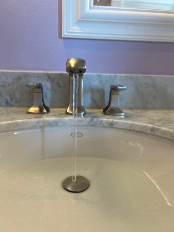 Completed installation of a three-piece widespread bathroom faucet with brushed nickel finish on white porcelain sink. Connected hot and cold water supply lines using braided stainless steel flexible hoses to existing shut-off valves, verified proper water flow and pressure, and tested for leaks at all connection points. Installation includes functional drain assembly with chrome P-trap configuration and garbage disposal unit integration under sink.
