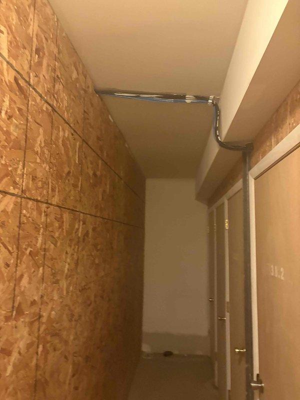 Responded to service call for clogged drain/sink at residential property. Upon arrival, accessed plumbing system through utility corridor with exposed OSB wall construction and overhead piping. Successfully cleared blockage and restored proper drainage function, with documentation photos taken of work area and access points for service records.