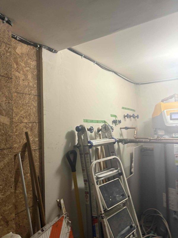 Responded to service call for clogged drain/sink at residential property. Upon arrival, accessed plumbing system through utility corridor with exposed OSB wall construction and overhead piping. Successfully cleared blockage and restored proper drainage function, with documentation photos taken of work area and access points for service records.
