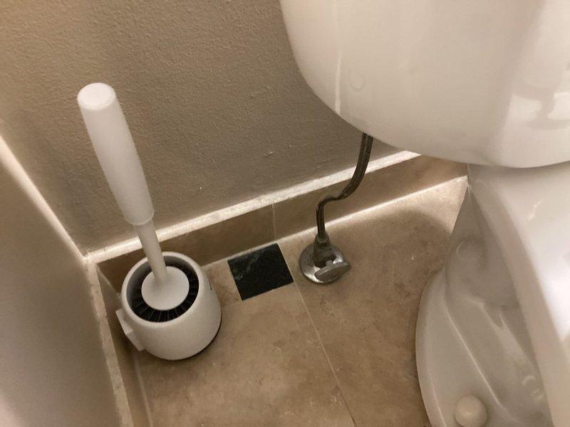 Responded to service call for toilet running slowly. Upon inspection, removed tank lid and examined flush mechanism components. Found fill valve, flapper valve, and float ball assembly showing signs of wear and mineral deposits affecting proper operation. Inspected overflow tube and refill tube connections to ensure proper water flow and tank refill cycle. Assessed internal tank components for functionality and identified cause of slow running issue. Documented tank interior condition with photographs showing standard flush mechanism layout including blue-capped fill valve, black overflow tube, red rubber flapper, and yellow float ball with chain assembly. Verified all connections between fill valve and overflow tube were secure. Photographed work area and tools used during diagnostic inspection.