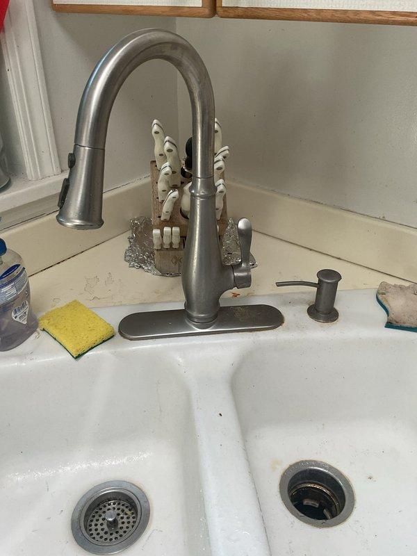 Completed installation of new garbage disposal unit under kitchen sink. Mounted red and stainless steel disposal assembly to sink drain with proper electrical connections and plumbing integration. Connected discharge line with corrugated drain hose to existing PVC trap configuration. Verified proper operation of disposal unit and checked all connections for leaks. Installation completed with disposal fully functional and ready for use.